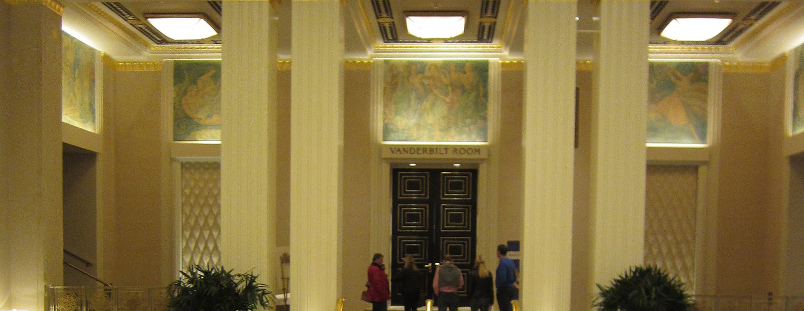 The lobby of a grand New York hotel, with a mosaic floor and tall columns